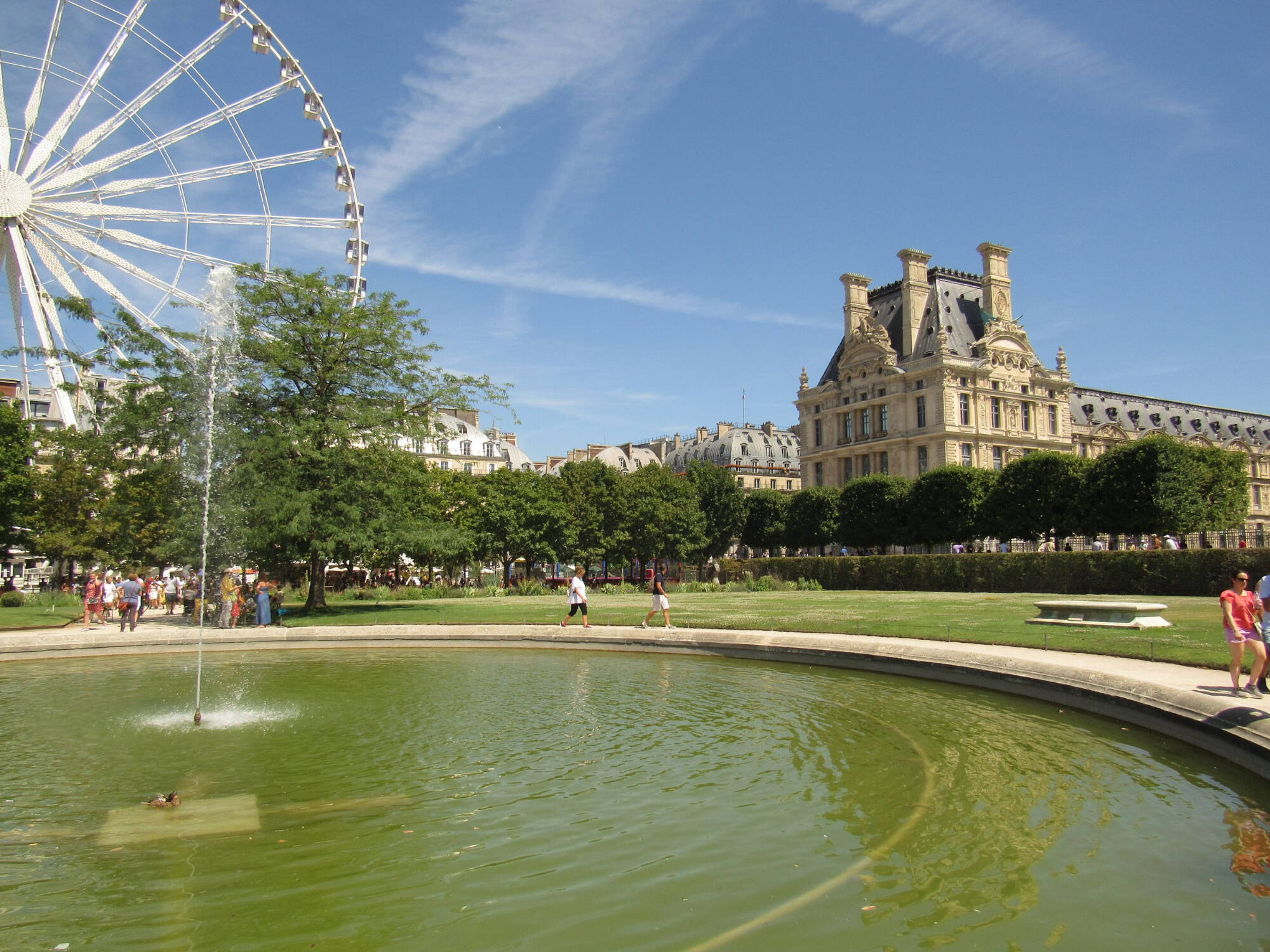 Large Round Fountain in Foreground with Ferris Wheel and Large Old Building in Background